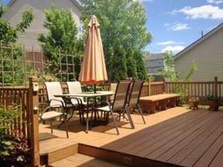 composite deck in a backyard and furnished with table and shade umbrella